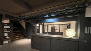 A modern hotel lobby with a staircase, a reception desk, and a digital directory. - Yusai Bekkan (Minamioguni)