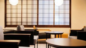 A traditional Japanese-style interior with tatami mat flooring, low tables, and chairs.