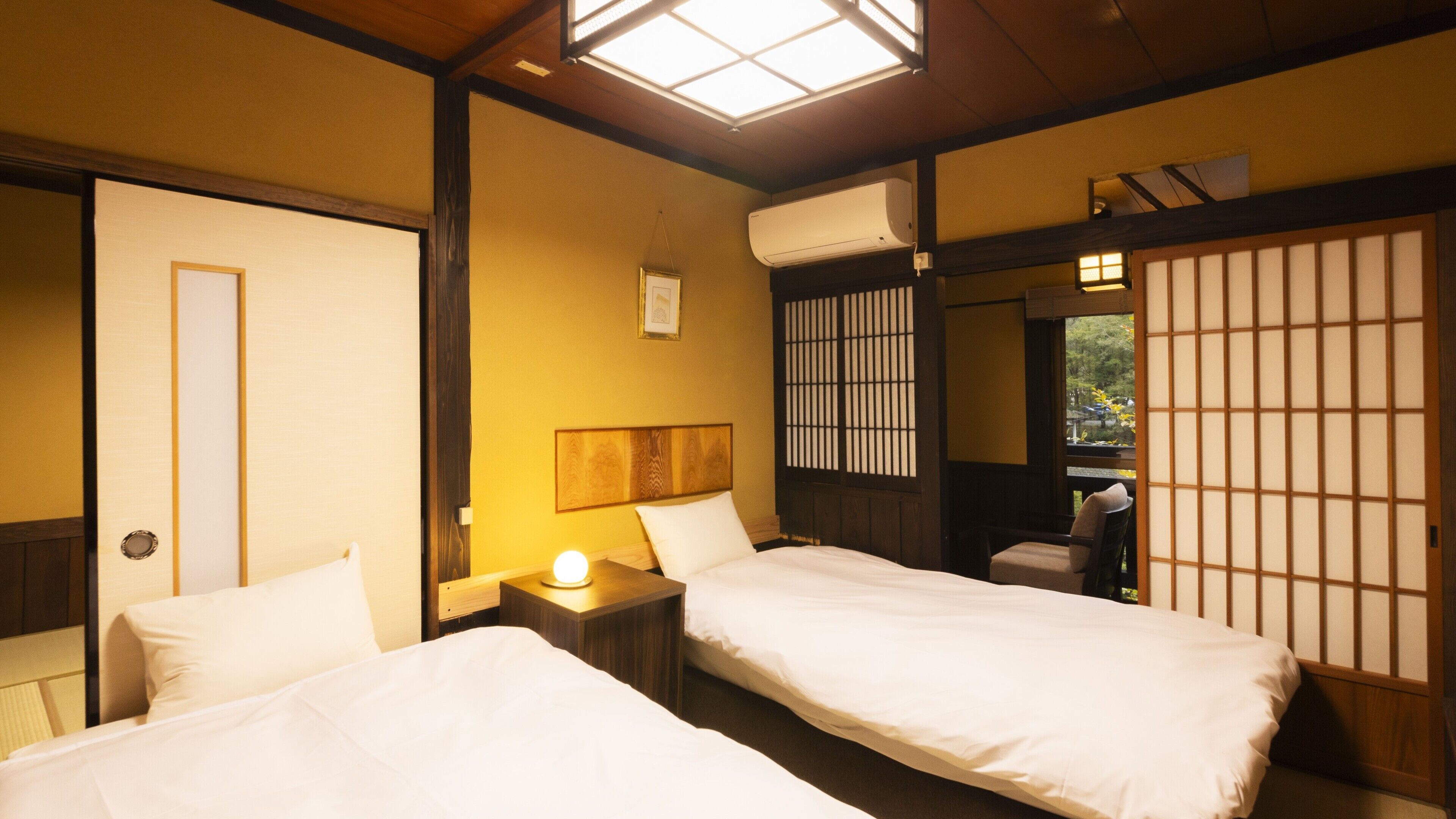 A traditional Japanese-style room with two beds, a wooden ceiling, and a sliding door.