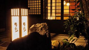 A traditional Japanese building with illuminated signage and a rock in the foreground. - Yusai Bekkan (Minamioguni)
