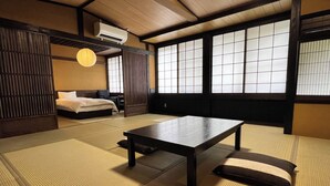 A traditional Japanese room with tatami flooring, a low table, a bed, and sliding doors. - Yusai Bekkan (Minamioguni)