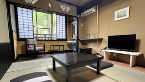 A traditional Japanese-style room with tatami flooring, a low table, a sofa, and a television on a stand. - Yusai Bekkan (Minamioguni)