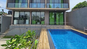Um edifício moderno de dois andares com piscina, janelas amplas e varanda.