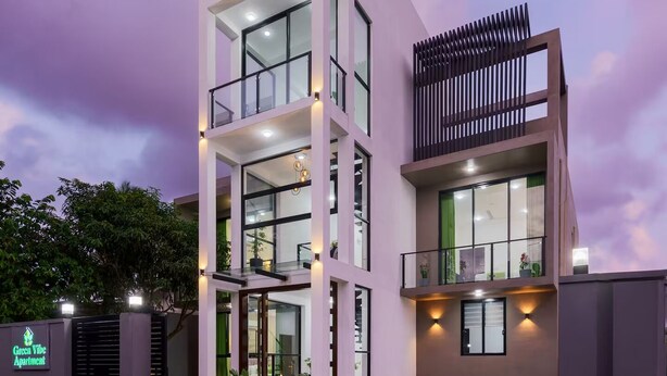 Um edifício moderno de vários andares com teto plano, grandes janelas e portão fechado.