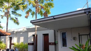 A residential building with numbered doors, a parked scooter, and palm trees. - Damarya Villa Canggu (Canggu)