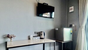 A small kitchenette with a white countertop, a kettle, a small refrigerator, and a TV mounted on the wall. - OYO 75530 By the dam cafe and farmstay (Plai Phraya)