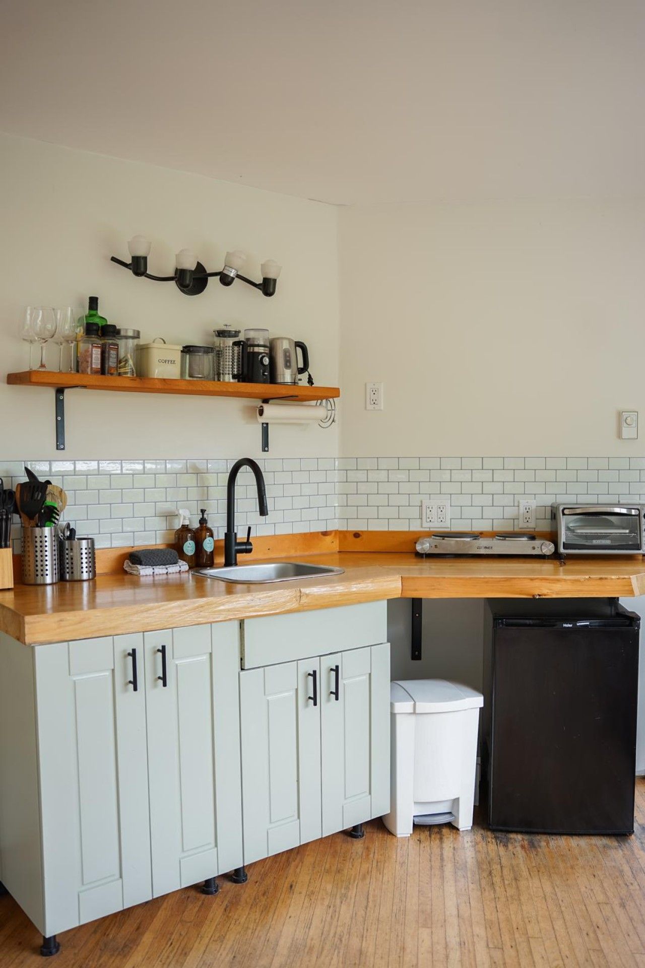 Una cocina con encimera de madera, un lavamanos, un tostador y un refrigerador.