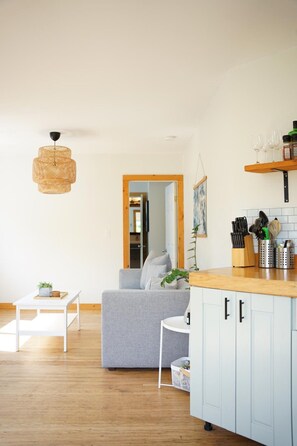 Ein modernes Wohnzimmer mit einem grauen Sofa, einem weißen Couchtisch und einer hängenden gewobenen Leuchte.