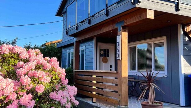 Un bâtiment à deux étages doté d’une terrasse en bois, d’une grande fenêtre et d’une porte sur laquelle est apposée une enseigne.
