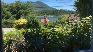 Une vue sur un lac, avec une montagne en arrière-plan, entouré de verdure et d’un bâtiment doté d’un toit rouge.