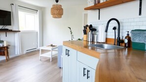Une cuisine moderne avec des meubles de couleur bois clair, un plan de travail en bois, un évier encastré et un luminaire suspendu.