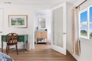 A room with a wooden desk, a chair, a framed painting, a mirror, a wooden cabinet, and a window with curtains. - 4bedroom|Sleep10|Ocean Views|Hot Tub|La Jolla (San Diego)