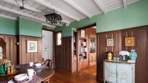 A dining area with a wooden table set for four, surrounded by wooden paneling and a green wall.