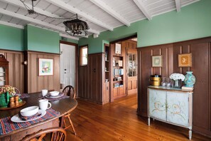 Comedor con mesa de madera dispuesta para cuatro personas, rodeada de paneles de madera y una pared verde.
