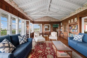 A spacious living room with a high ceiling, wooden paneling, large windows, and a view of the outdoors. - 4bedroom|Sleep10|Ocean Views|Hot Tub|La Jolla (San Diego)