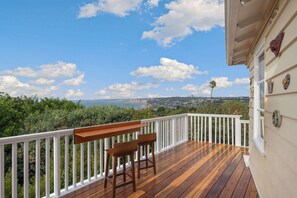 A wooden deck with a white railing, two wooden benches, and a view of the sea and hills. - 4bedroom|Sleep10|Ocean Views|Hot Tub|La Jolla (San Diego)