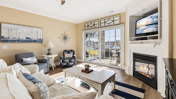A living room with a fireplace, a television, and a view of the outdoors.