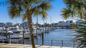 A marina with docked boats, a wooden walkway, and residential buildings in the background.