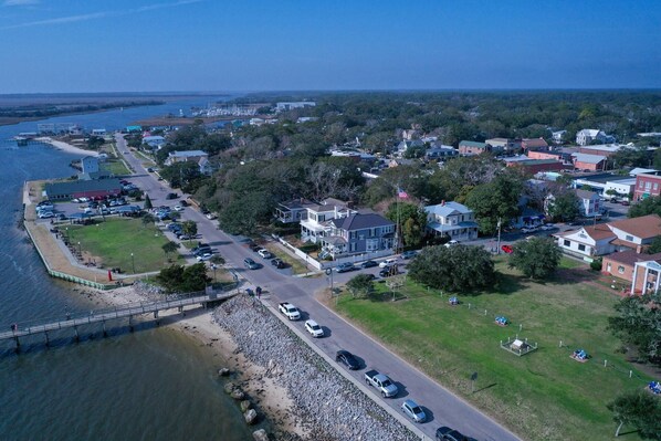 An aerial view of a coastal town with a marina, residential houses, and a bridge connecting the shore to the mainland.