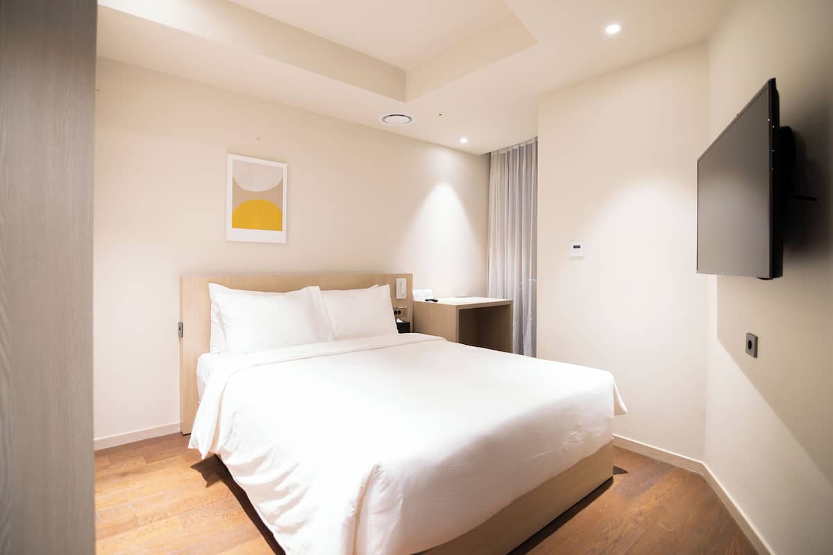 A hotel room with a large bed, a TV mounted on the wall, and a small table.