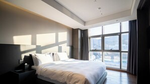 A modern hotel room with a large bed, a nightstand, and a view of the city through large windows. - HOMESRED MYEONGDONG (Seoul)