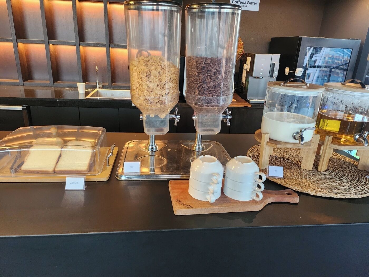 Kaffestation med to dispensere, et brødudstilling og en mælkedispenser.