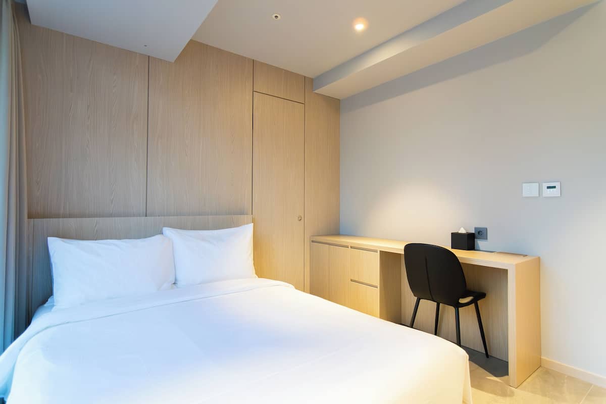 A modern bedroom with a large bed, a desk, and a chair.