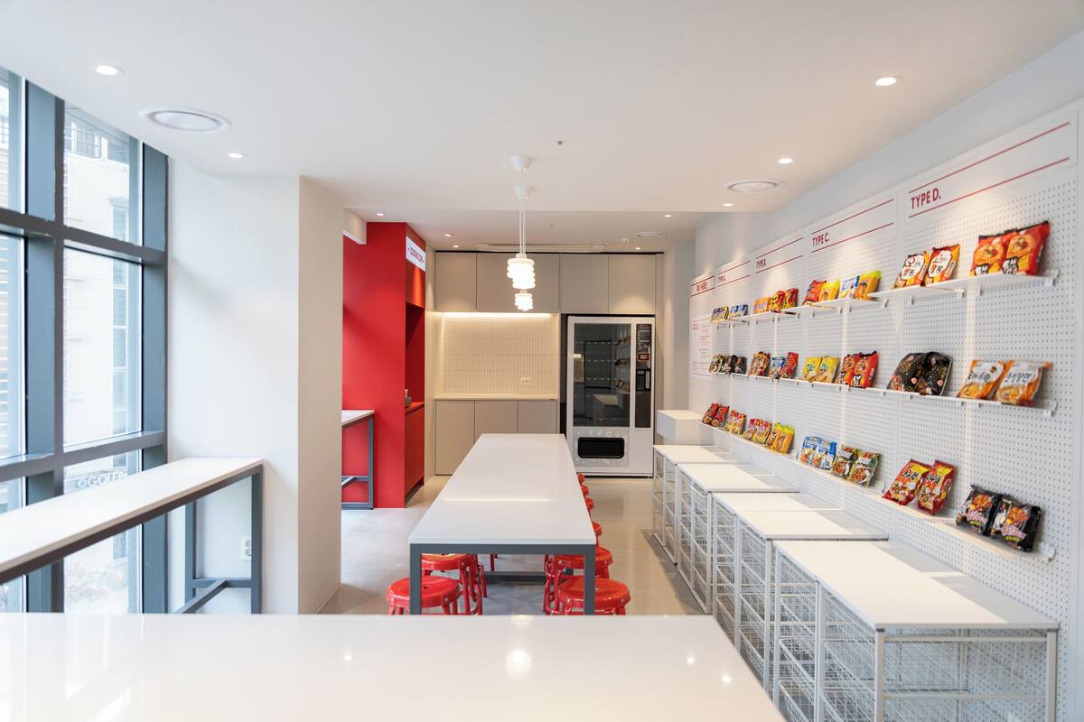 A modern kitchen with white countertops, red accents, and a wall displaying various snack packages.