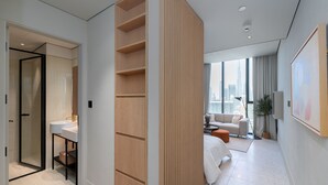 A modern hotel room with a large window, a sofa, a coffee table, and a bathroom with a sink and shower. - Trendy Studio w/ Burj Khalifa View (Dubai)