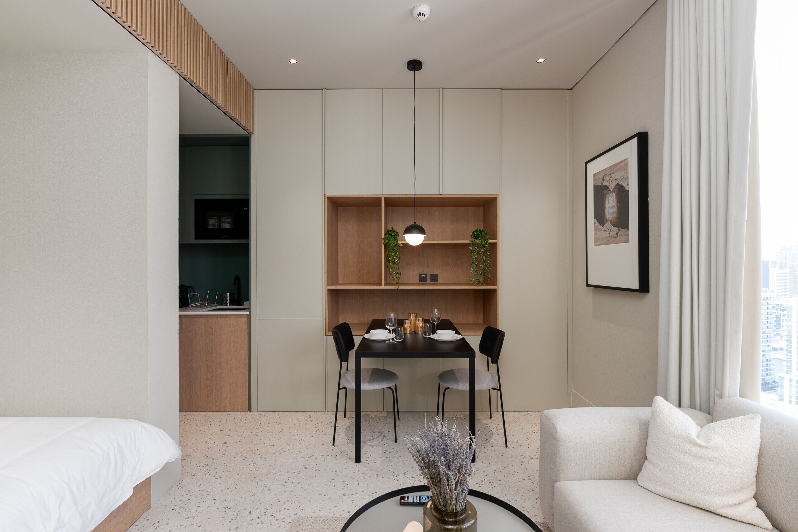 A modern hotel room with a dining area, a sofa, and a bed.