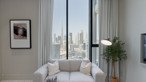 A modern living room with a large window, a sofa, a floor lamp, and a framed picture on the wall. - Trendy Studio w/ Burj Khalifa View (Dubai)