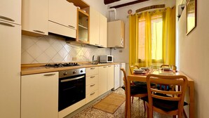 Una cocina compacta con estufa a gas, horno, microondas y un comedor con mesa y sillas.
