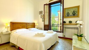 A neatly made bed with white linens, a wooden headboard, and two bedside lamps. - Residence Moretta (Historical Center) (Venecia)