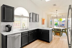 A modern kitchen with black cabinets, a white countertop, and a built-in dishwasher.