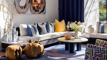 A modern living room with a grey sofa, blue and yellow cushions, a glass coffee table, and decorative vases.