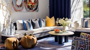 A modern living room with a grey sofa, blue and yellow cushions, a glass coffee table, and decorative vases. - Yallungah Boutique Hotel by Travellers (Orange)