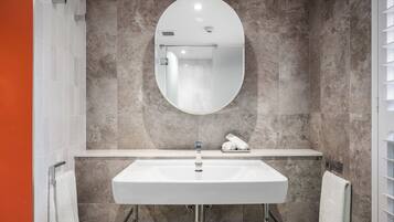 A modern bathroom with a large oval mirror, a rectangular sink, and a towel rack.