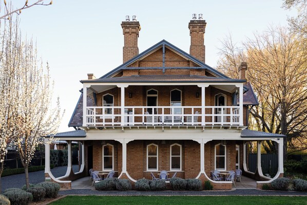 A two-story brick house with a balcony, a covered porch, and a well-maintained garden. - Yallungah Boutique Hotel by Travellers (Orange)
