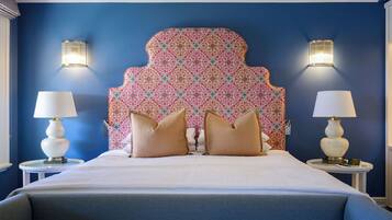 A hotel room with a large bed, two bedside lamps, and a patterned headboard.