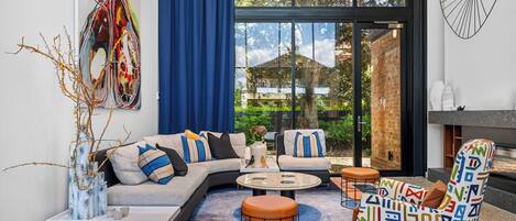 A modern living room with a sectional sofa, a coffee table, a patterned armchair, and a fireplace.