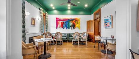 A dining area with wooden flooring, a ceiling fan, and a colorful abstract painting on the wall.