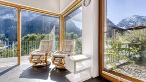 Un balcón con dos sillones de cuero y una mesita blanca, con vistas a un paisaje montañoso.