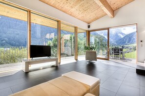 A spacious living room with large windows, a flat-screen TV, and a comfortable seating area. - Panorama Chalet Bellavista (Brand)