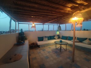A cozy outdoor seating area with a thatched roof, a sofa set, and a small table. - Pretty Riad La Médina   (Marrakech)