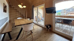 Un intérieur en bois comprenant un coin repas, un escalier et un téléviseur fixé au mur.