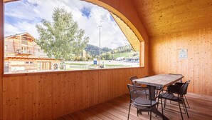 Un intérieur en bois avec une grande fenêtre en arc de cercle, une table et des chaises.