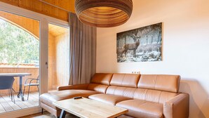 Un salon moderne avec un canapé en cuir, une table basse en bois et une grande fenêtre donnant sur la forêt.