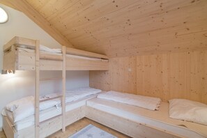 Une petite cabane en bois avec des lits superposés et un lit simple.