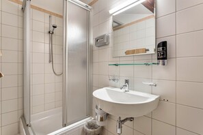 Une salle de bain équipée d’une douche, d’un lavabo, d’un miroir et d’un porte-serviettes.
