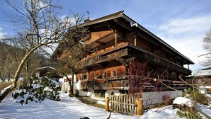 A wooden chalet with multiple balconies, a snow-covered ground, and a clear sky.